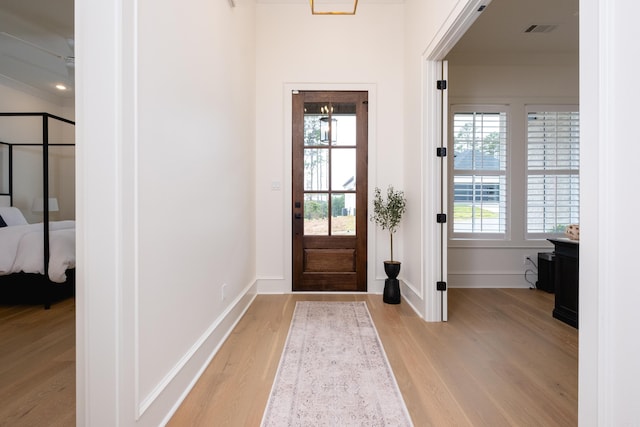 doorway featuring light wood-type flooring and crown molding