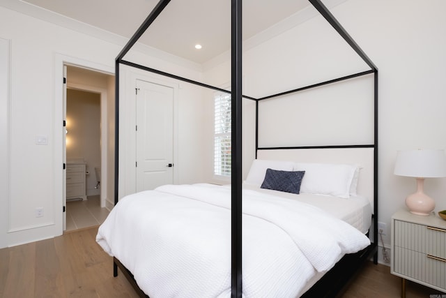 bedroom with ensuite bathroom and hardwood / wood-style flooring