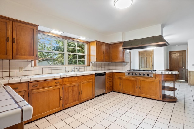 kitchen featuring stainless steel appliances, tile countertops, sink, kitchen peninsula, and decorative backsplash