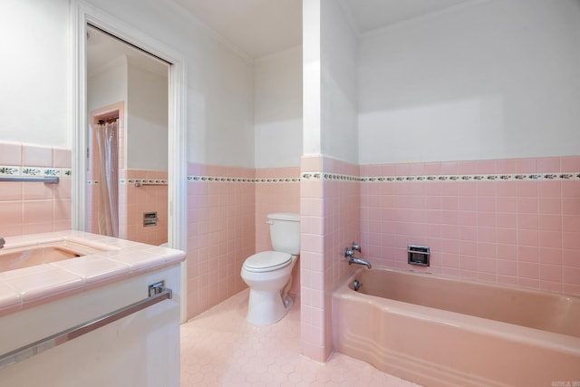 bathroom featuring vanity, crown molding, toilet, a bathtub, and tile walls