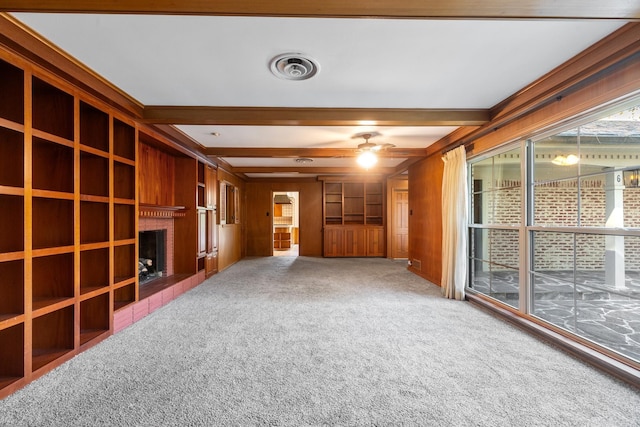 spare room featuring carpet flooring, beam ceiling, wood walls, a tile fireplace, and ceiling fan