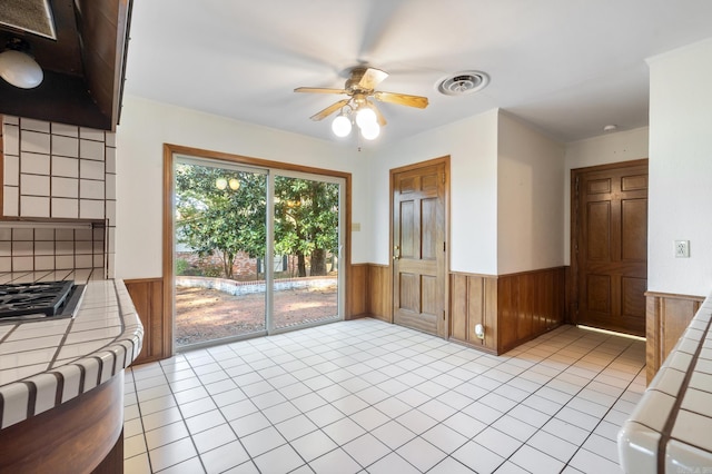 interior space featuring wood walls, ceiling fan, and light tile patterned flooring