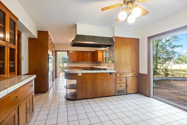 kitchen with tile counters, oven, and plenty of natural light