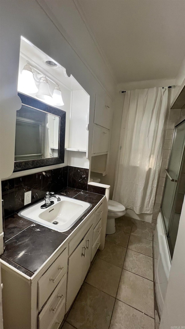 full bathroom featuring tile patterned floors, combined bath / shower with glass door, decorative backsplash, toilet, and vanity