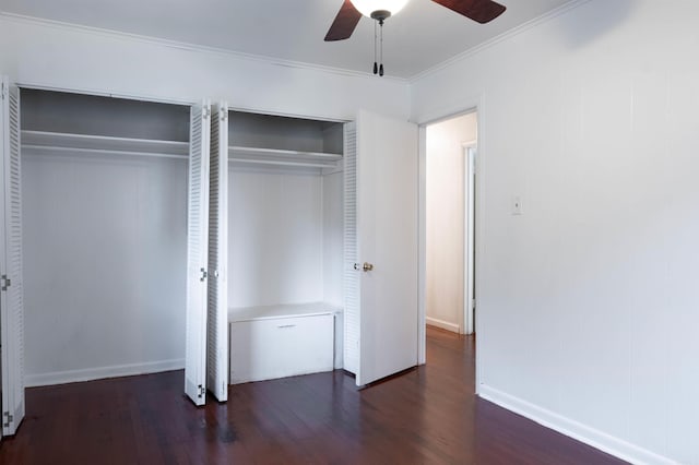 unfurnished bedroom featuring ceiling fan, dark hardwood / wood-style flooring, ornamental molding, and multiple closets