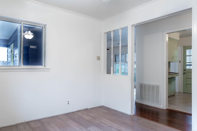 spare room featuring a wealth of natural light, wood-type flooring, and ornamental molding