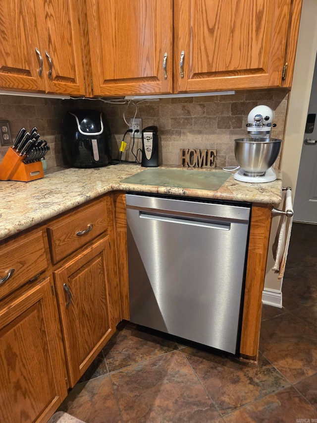 kitchen featuring light stone countertops, backsplash, and stainless steel dishwasher