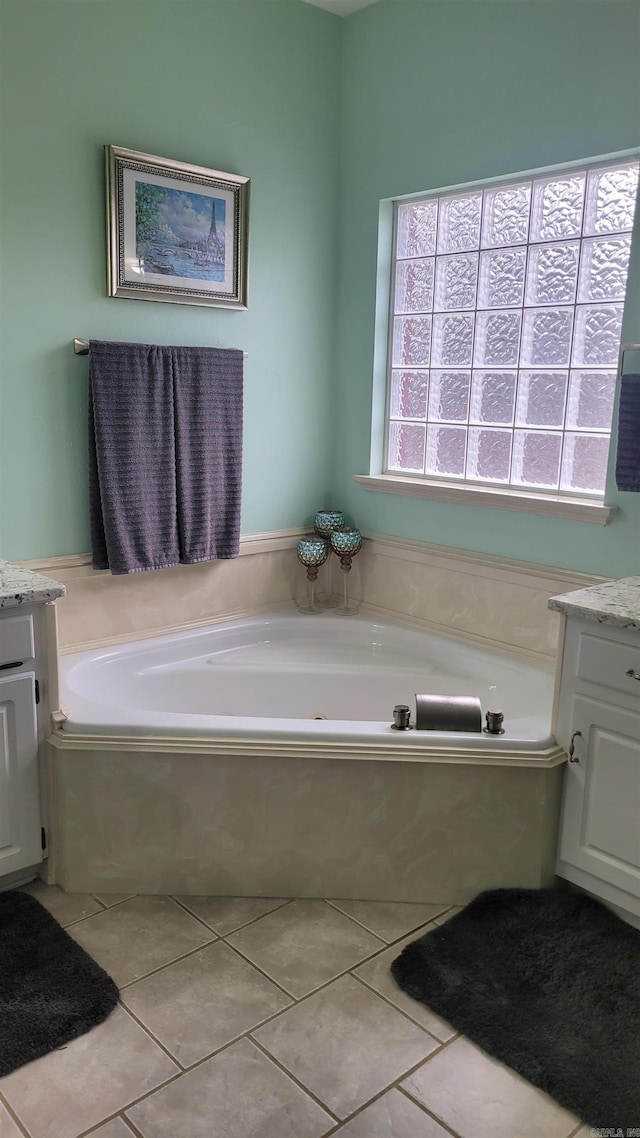 bathroom featuring tile patterned floors, vanity, and a relaxing tiled tub