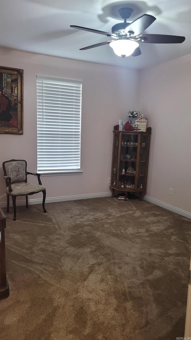 sitting room with ceiling fan and dark colored carpet