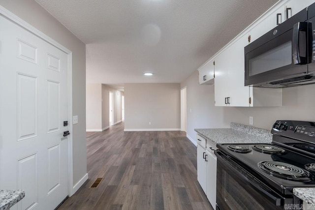 kitchen with dark hardwood / wood-style floors, white cabinetry, black appliances, and a textured ceiling