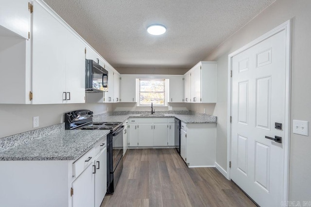 kitchen with white cabinetry, a textured ceiling, black appliances, and hardwood / wood-style flooring