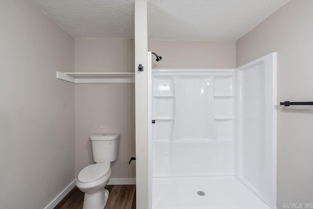 bathroom featuring hardwood / wood-style floors, walk in shower, a textured ceiling, and toilet