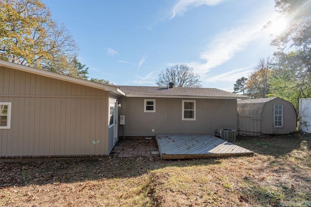 rear view of house with a storage shed, a lawn, central AC, and a deck