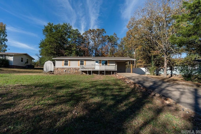 view of front of property with a carport, a front lawn, a deck, and a storage shed