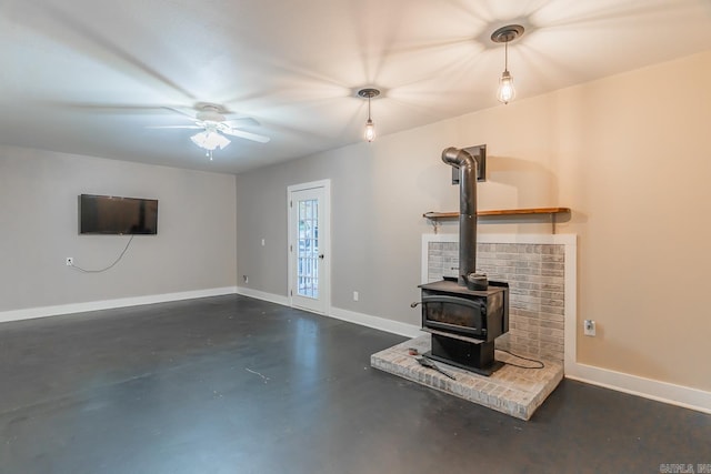 unfurnished living room with a wood stove and ceiling fan