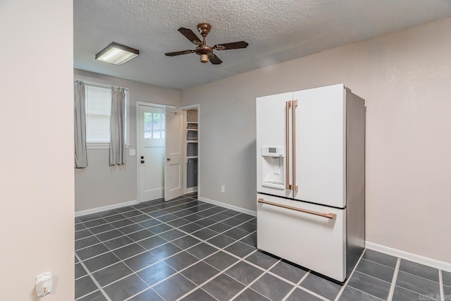 interior space with ceiling fan, white cabinetry, dark tile patterned floors, and white fridge with ice dispenser