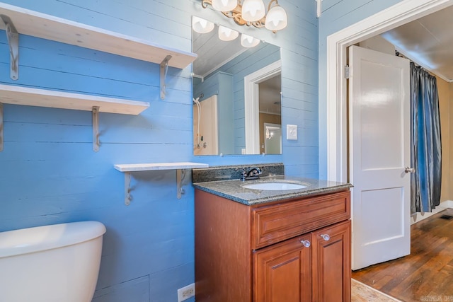 bathroom with vanity, hardwood / wood-style flooring, wooden walls, and toilet