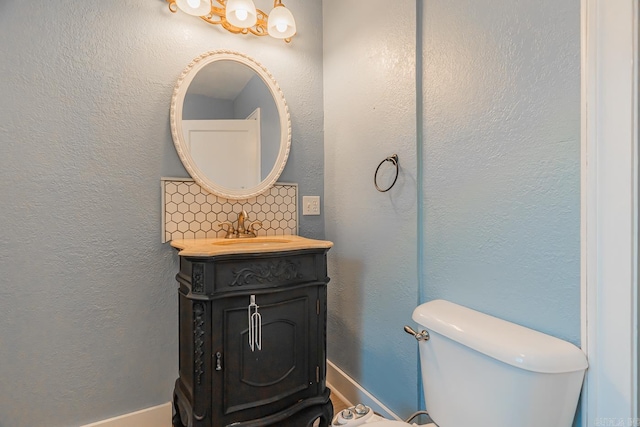 bathroom featuring vanity, toilet, and backsplash