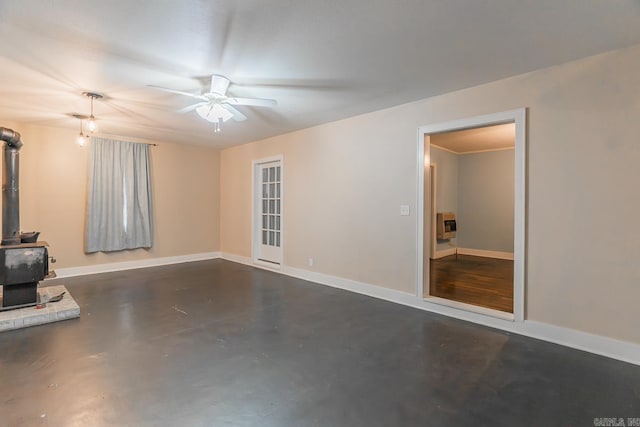 unfurnished living room with ceiling fan and a wood stove