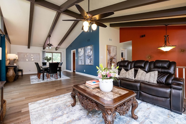 living room featuring ceiling fan, wood-type flooring, and vaulted ceiling with beams