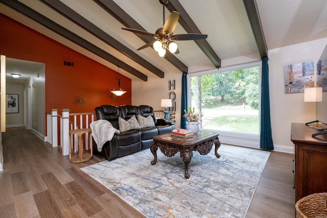 living room featuring hardwood / wood-style floors, vaulted ceiling with beams, and ceiling fan