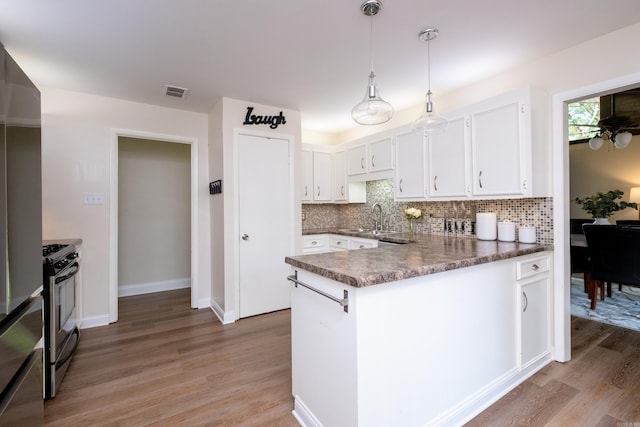 kitchen with white cabinetry, kitchen peninsula, stainless steel appliances, and light hardwood / wood-style floors