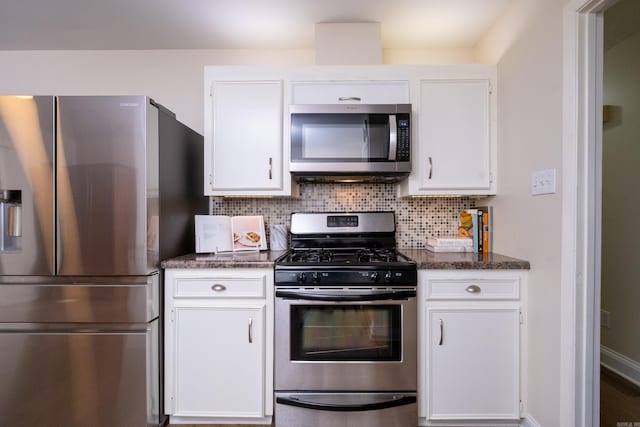 kitchen featuring white cabinets, dark stone countertops, appliances with stainless steel finishes, and tasteful backsplash