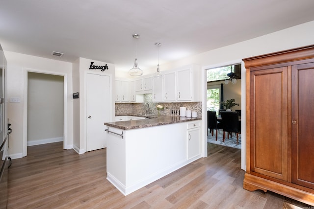 kitchen featuring white cabinets, ceiling fan, backsplash, pendant lighting, and light wood-type flooring