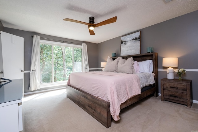 bedroom featuring a textured ceiling, light colored carpet, and ceiling fan