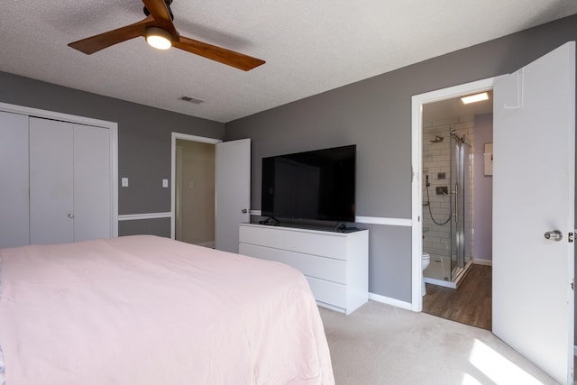 carpeted bedroom with ceiling fan, ensuite bath, a closet, and a textured ceiling