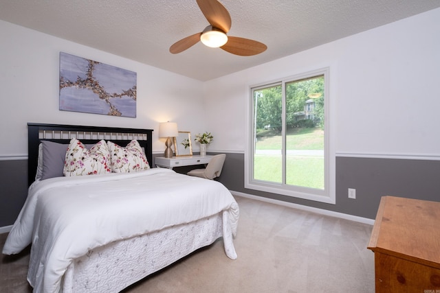 carpeted bedroom featuring ceiling fan and a textured ceiling