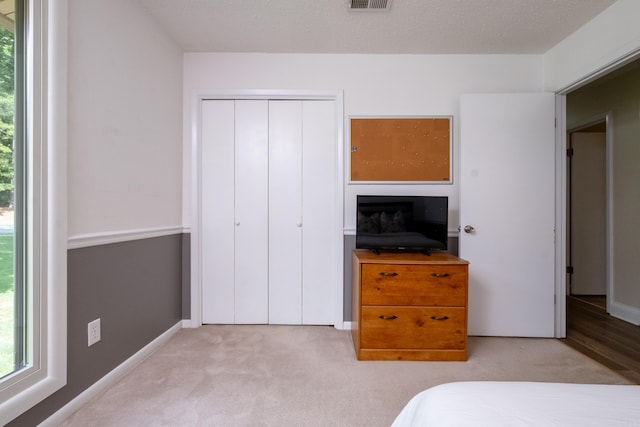 carpeted bedroom with a textured ceiling and a closet