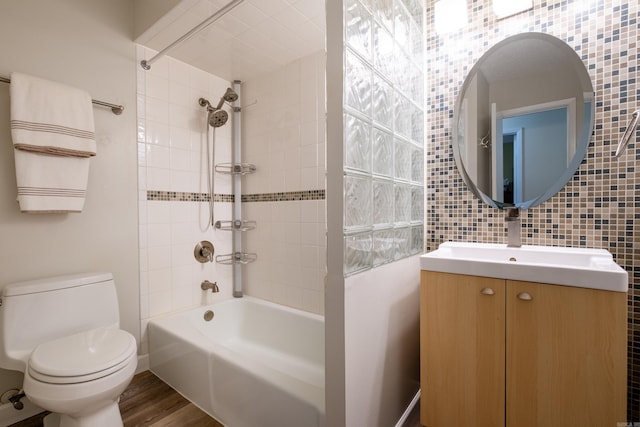 full bathroom featuring tile walls, vanity, hardwood / wood-style flooring, toilet, and tiled shower / bath