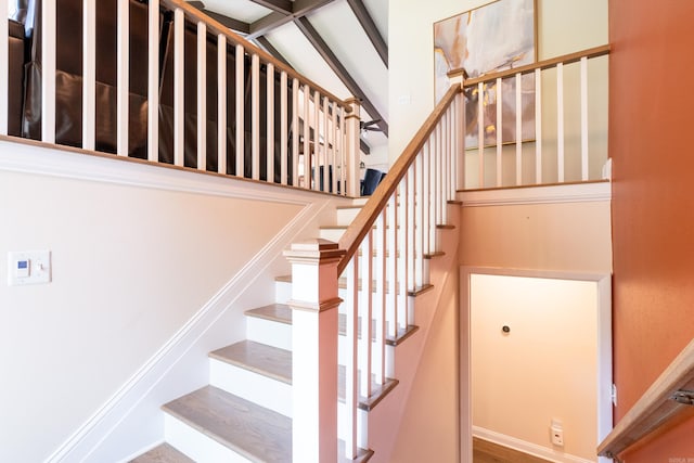 staircase featuring vaulted ceiling with beams