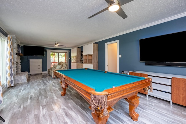 game room featuring a stone fireplace, a textured ceiling, billiards, and light hardwood / wood-style flooring