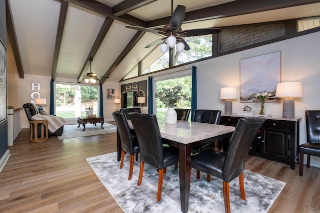 dining area featuring light wood-type flooring, ceiling fan, and vaulted ceiling with beams