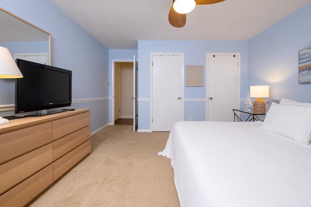 carpeted bedroom with ceiling fan and a textured ceiling