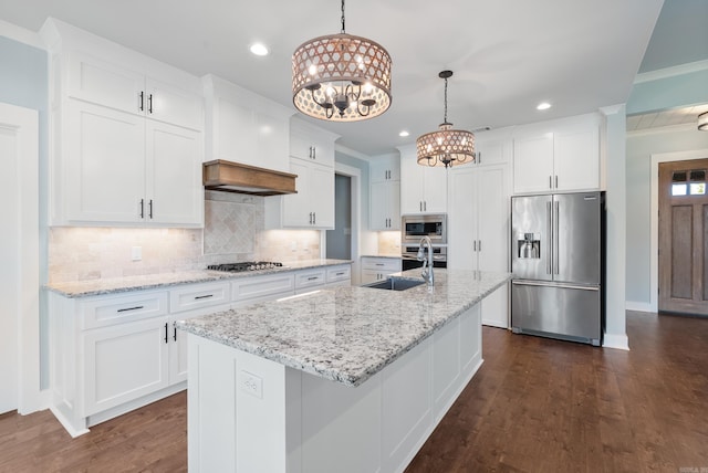 kitchen featuring white cabinetry, sink, appliances with stainless steel finishes, decorative light fixtures, and an island with sink