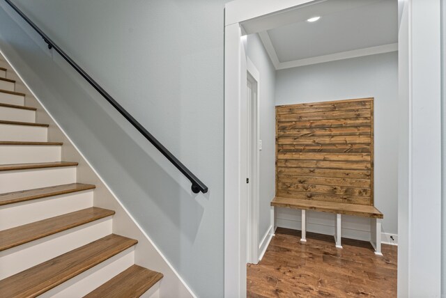 staircase with hardwood / wood-style floors and ornamental molding