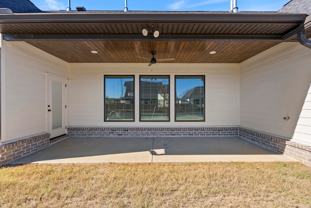 entrance to property with ceiling fan and a lawn