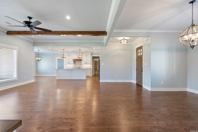 unfurnished living room featuring dark wood-type flooring, beamed ceiling, sink, and crown molding