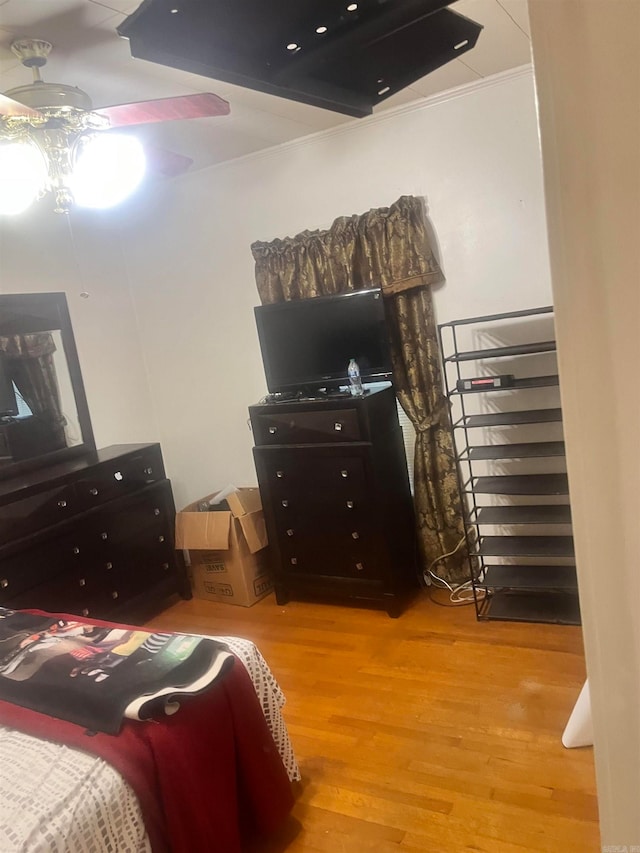 bedroom with wood-type flooring, ceiling fan, and crown molding