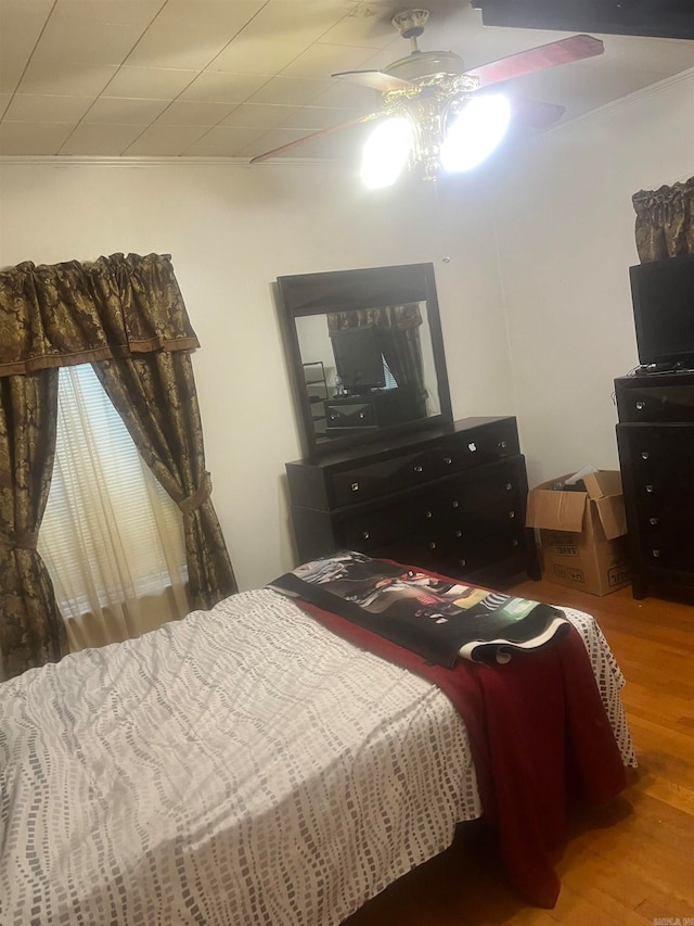 bedroom with hardwood / wood-style flooring, ceiling fan, and crown molding