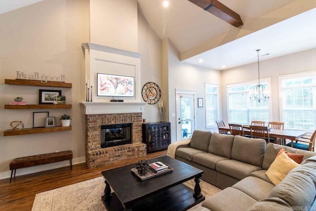 living room with a chandelier, high vaulted ceiling, a brick fireplace, and dark wood-type flooring