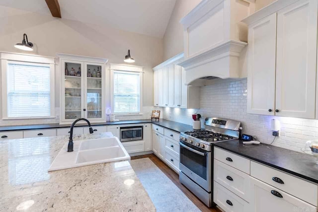 kitchen featuring white cabinetry, sink, lofted ceiling with beams, and appliances with stainless steel finishes