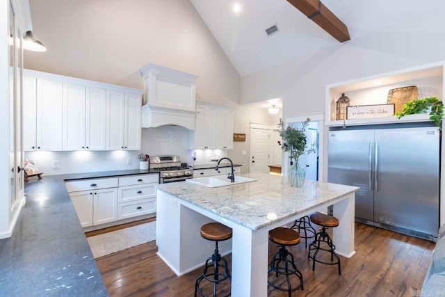 kitchen with a kitchen island with sink, dark wood-type flooring, high vaulted ceiling, and stainless steel appliances