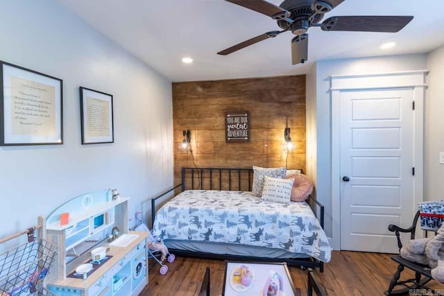 bedroom with dark hardwood / wood-style floors, ceiling fan, and wood walls