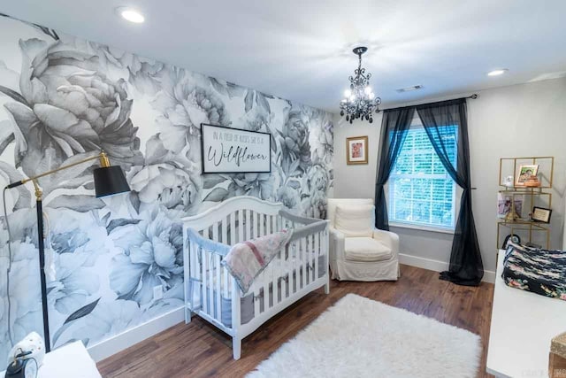 bedroom with a chandelier, dark hardwood / wood-style flooring, and a crib