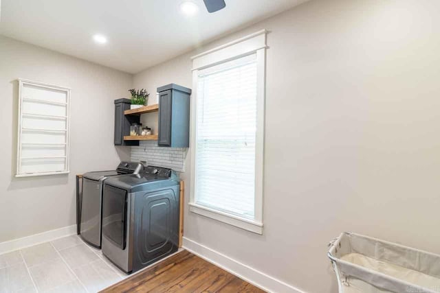 laundry area featuring cabinets, light hardwood / wood-style flooring, a wealth of natural light, and washing machine and clothes dryer