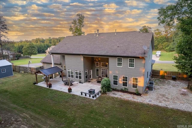 back house at dusk featuring cooling unit, a yard, and a patio